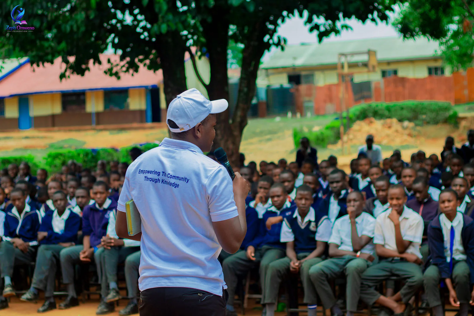 A ZOF mentor addressing a full assembly of students